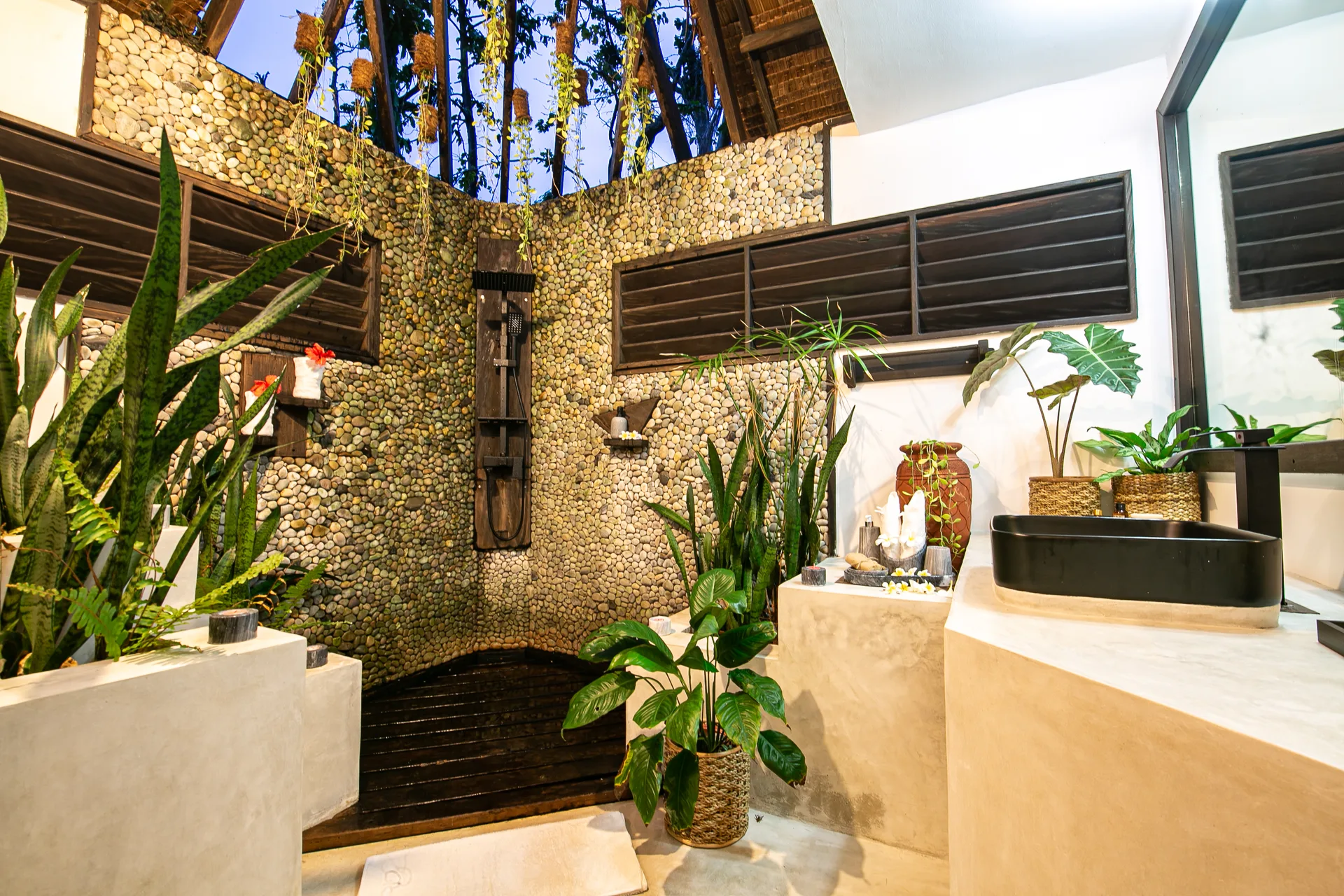 Open-air bathroom with pebble-stone walls and black stone vanity — Kawayan Villa Siargao