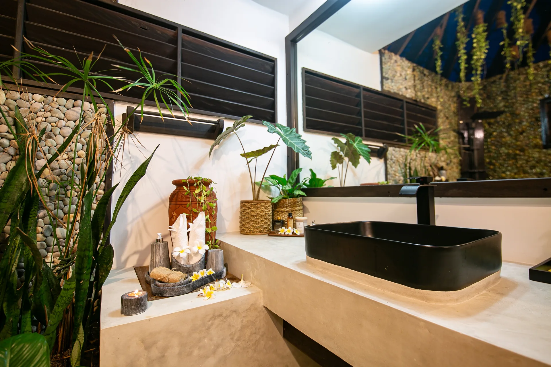 Bathroom detail with black stone basin, plants and traditional clay vessel — Kawayan Villa Siargao