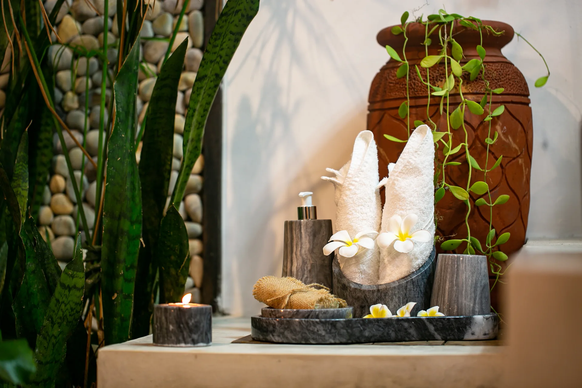 Bathroom amenities with rolled towels, frangipani flowers and candle — Kawayan Villa Siargao