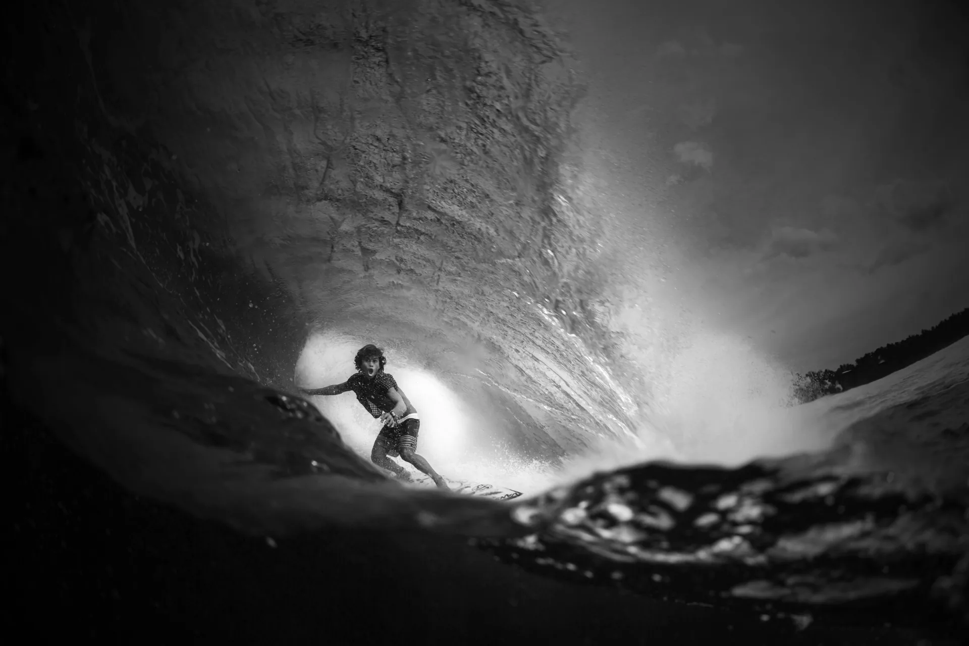 Black-and-white photograph of a surfer deep inside the barrel at Cloud 9, Siargao